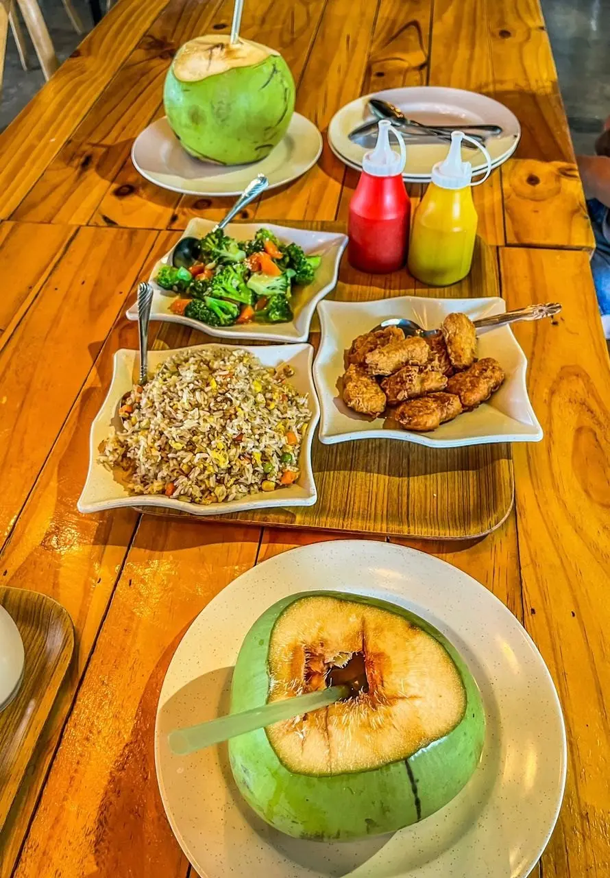 Fresh coconuts, salad and fried snacks laid out on a wooden cafe table