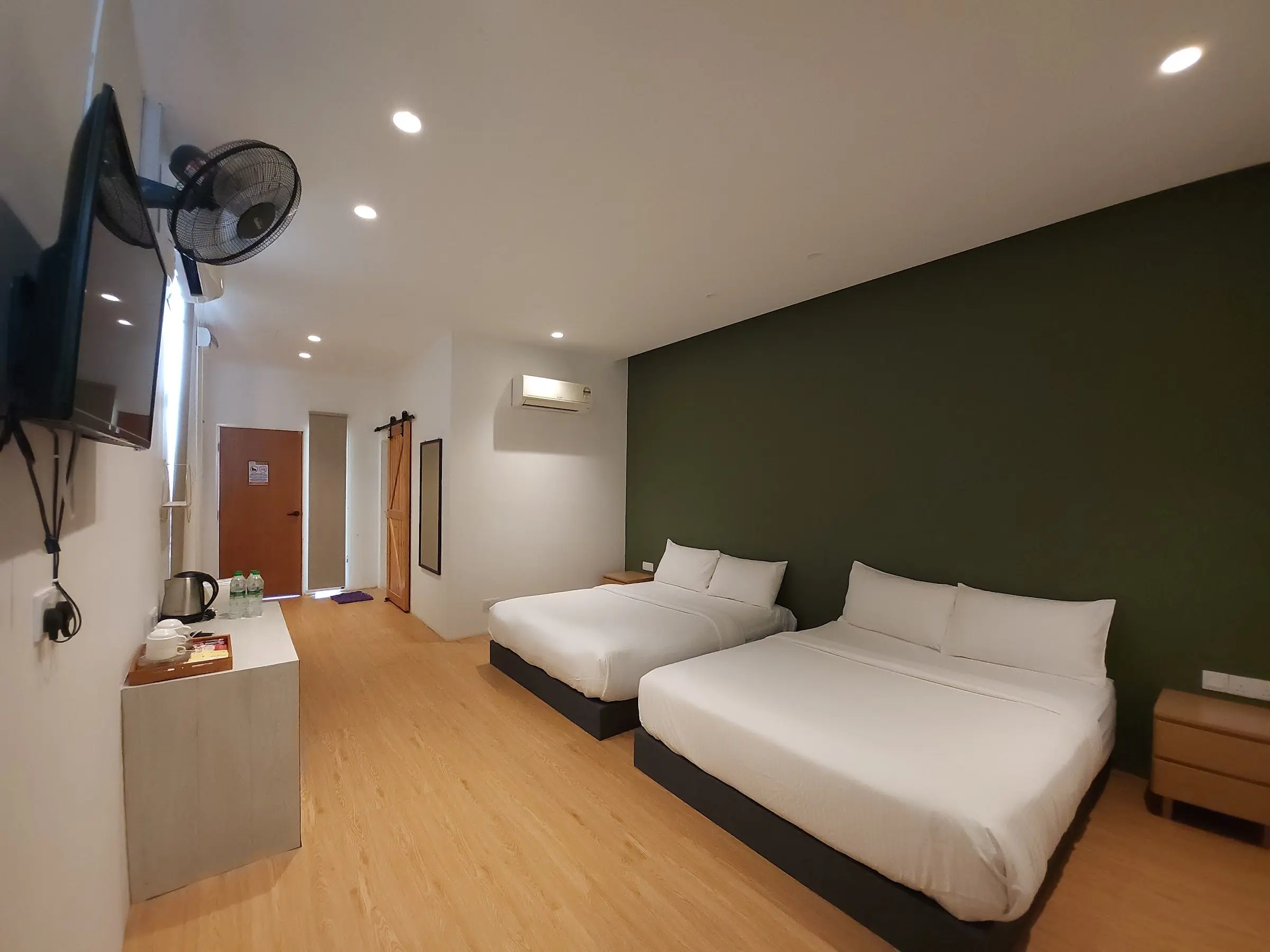 A Family Room with two beds against a deep green feature wall and timber floors
