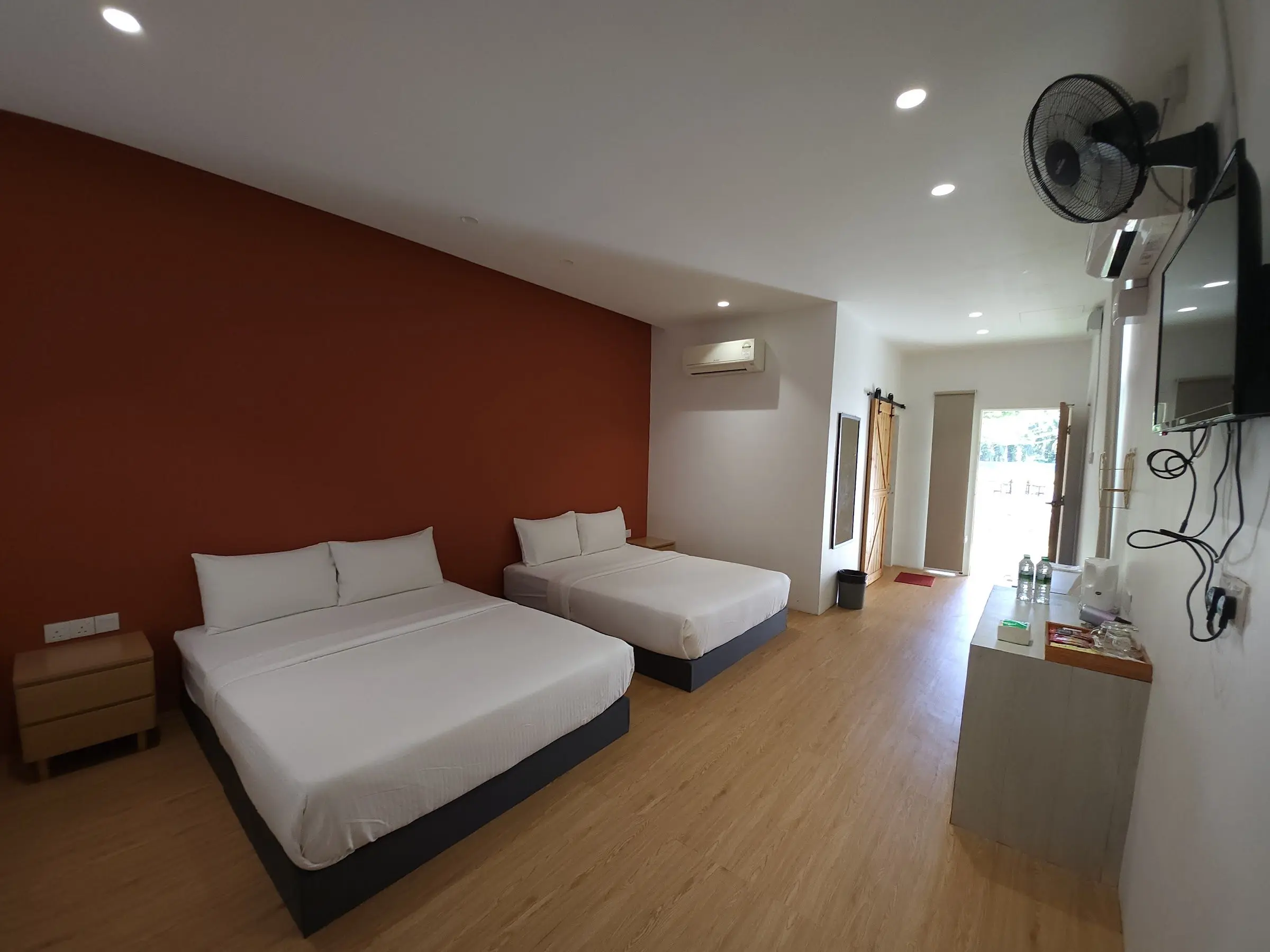 A Family Room with two beds, a terracotta feature wall and timber floors