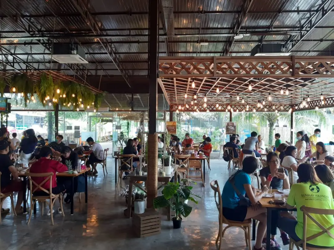 Guests fill the tables of the open-sided resort cafe under strings of warm bulbs