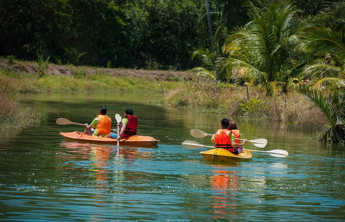 Two kayaks with paddlers in life jackets glide across a still green lake