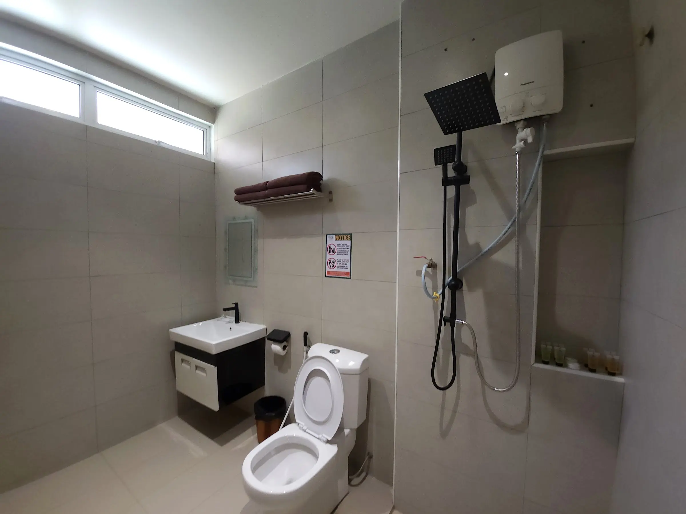 Ensuite bathroom with rain shower, water heater, toilet and vanity in grey tiles