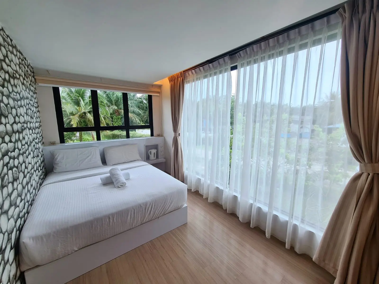 Container Room with a queen bed, stone-textured wall and floor-to-ceiling sheer curtains