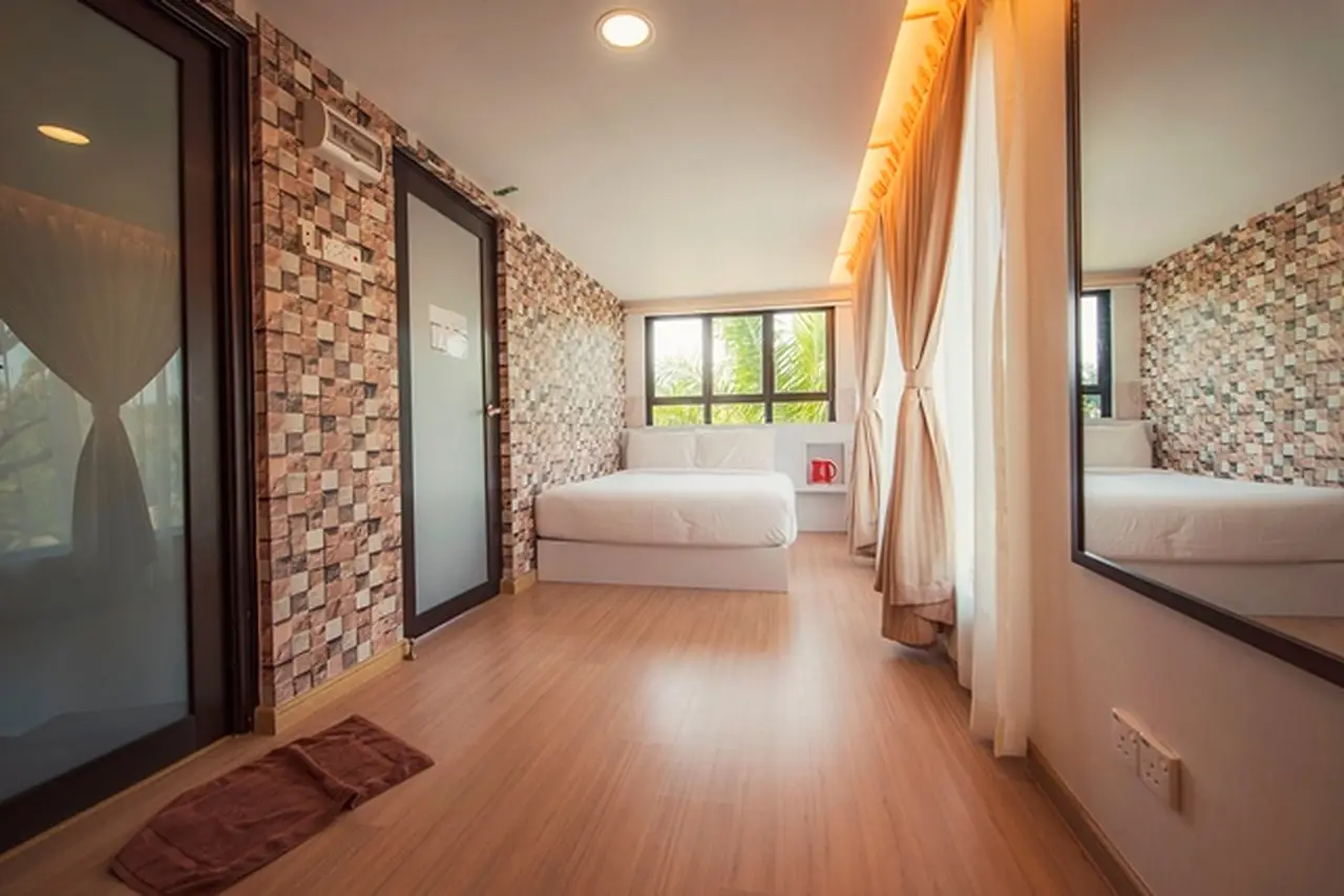Long view of a Container Room: brick-textured wall, mirror door and queen bed by the window