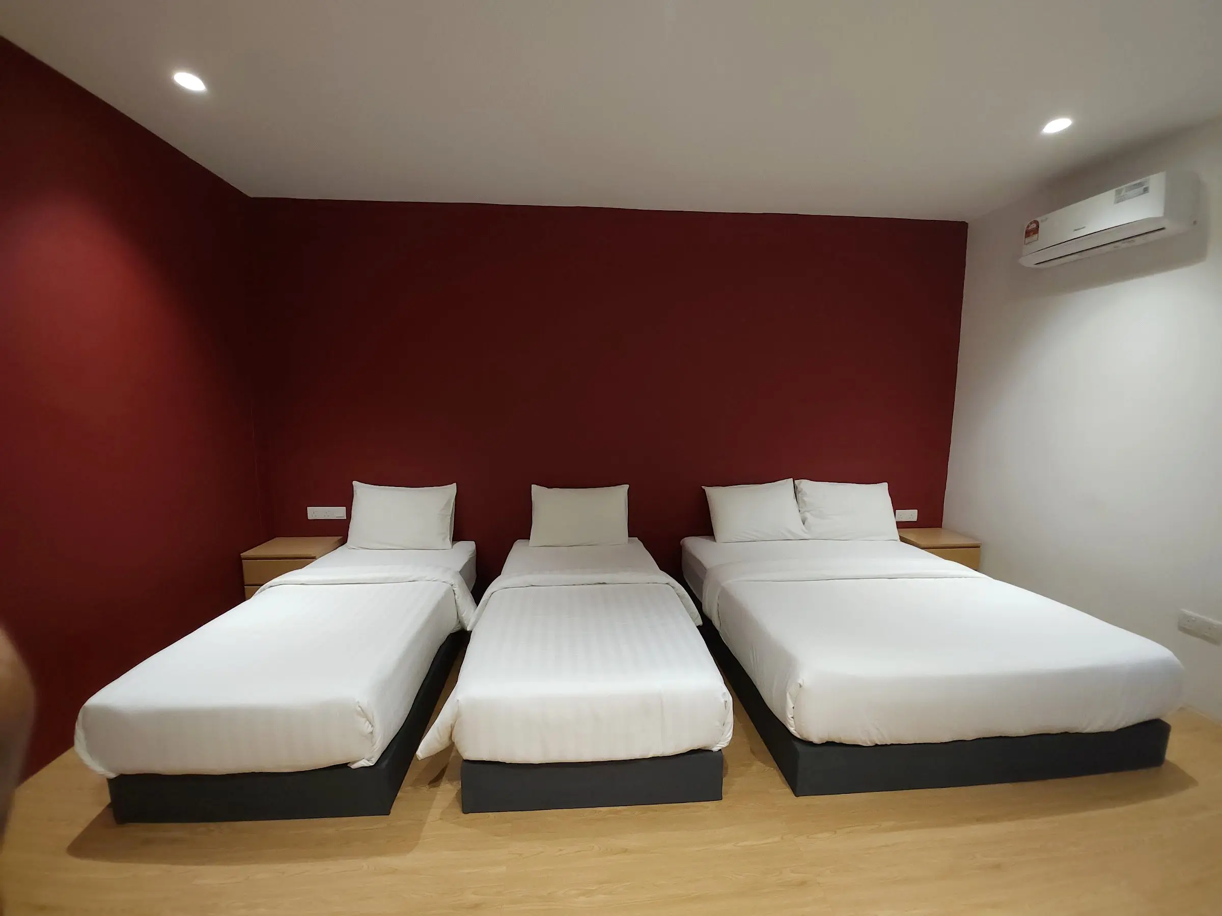Family Room with one queen and two single beds in white linen against a deep red feature wall
