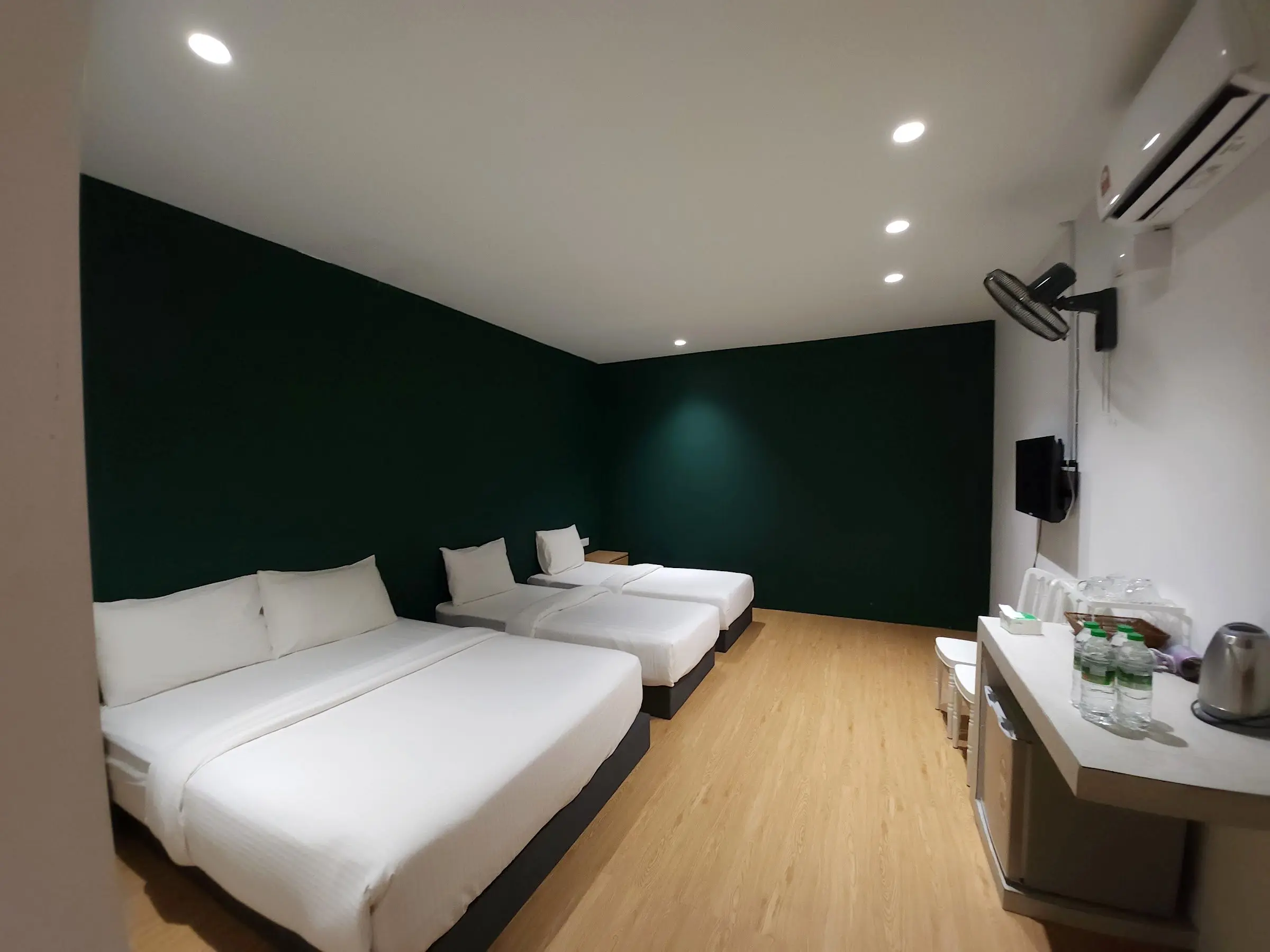 Family Room with a queen bed in front and two single beds beside a forest-green wall