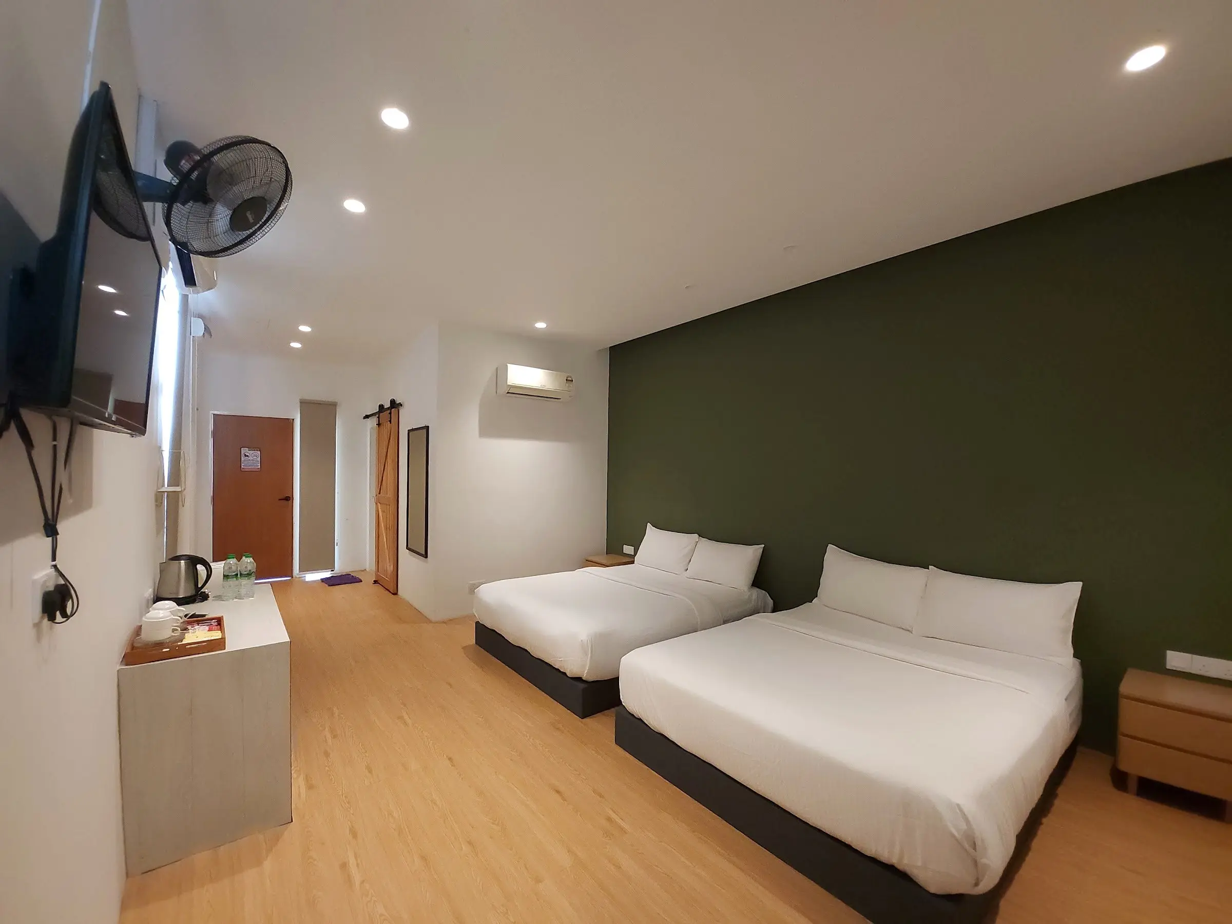 Family Room with two queen beds and bedside tables against an olive-green wall