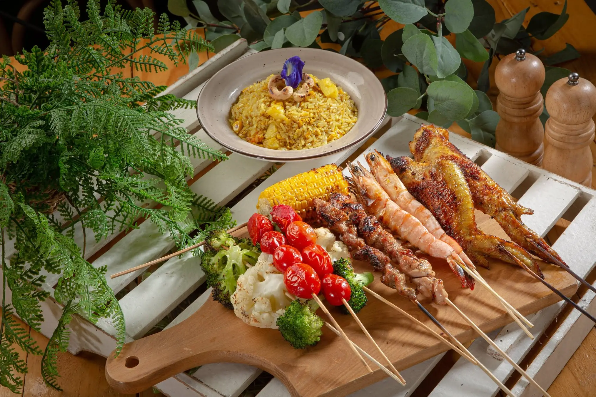 A platter of satay, grilled prawns, corn and vegetables with yellow rice